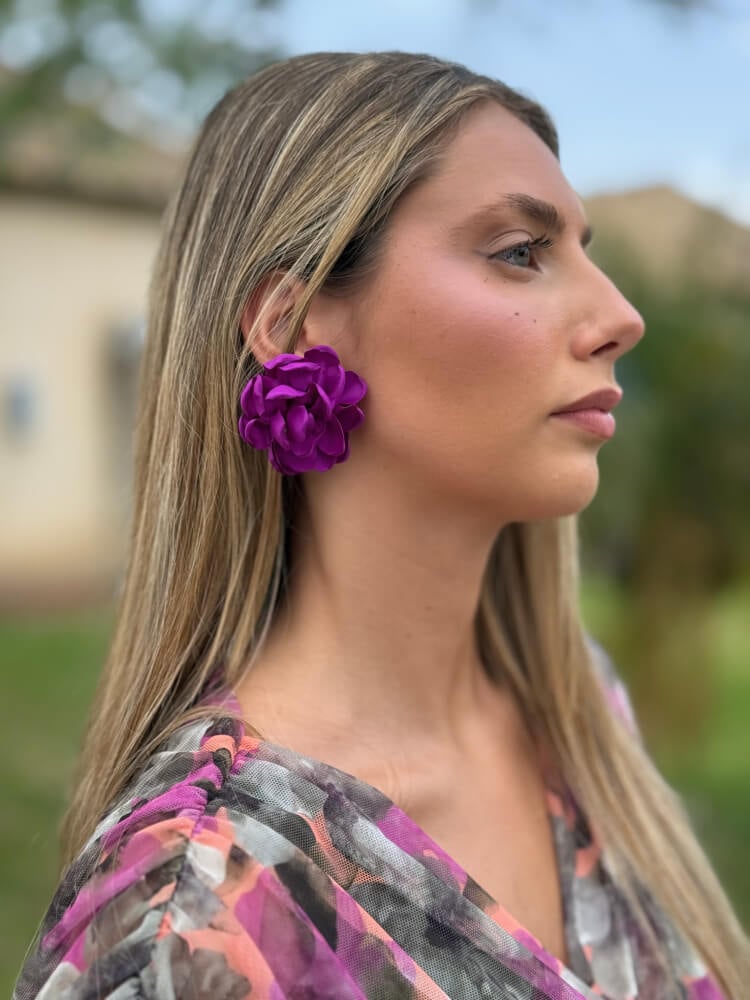 Pendientes de flor morada en tela puestos, iluminando el rostro con look veraniego