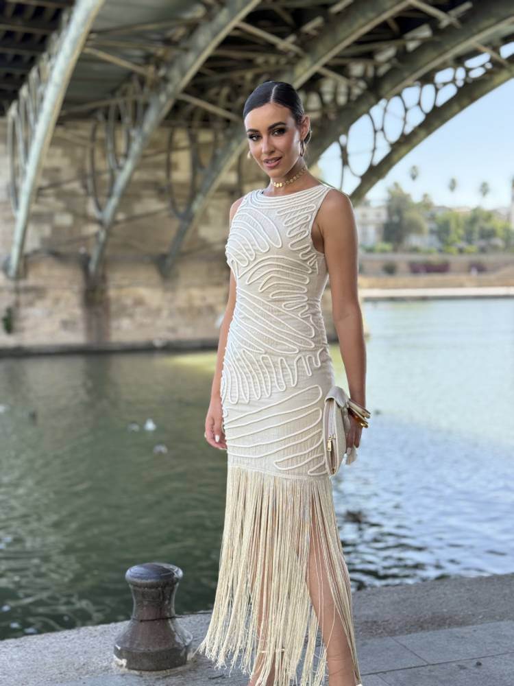 Vestido beige de invitada de boda con detalle de flecos en la falda.